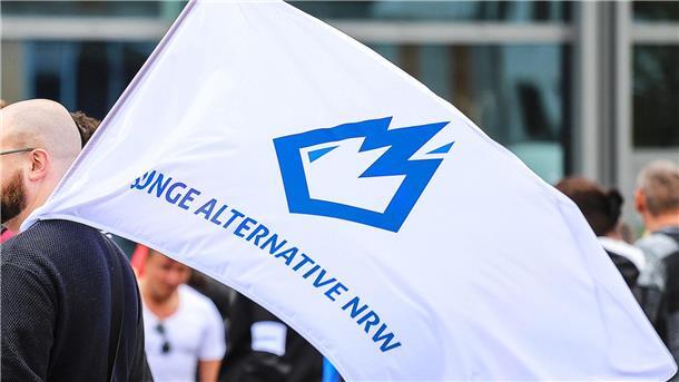 Ein Mitglied der „Jungen Alternative“ (JA) trägt auf einer Wahlkampfveranstaltung in Dortmund eine Fahne mit dem Logo der Organisation.