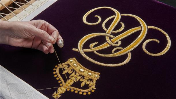 Neue Krönungsrobe für Queen Camilla enthüllt Ein Mitglied der Royal School of Needlework stickt den Schriftzug von Queen Camilla von Hand auf deren Robe.