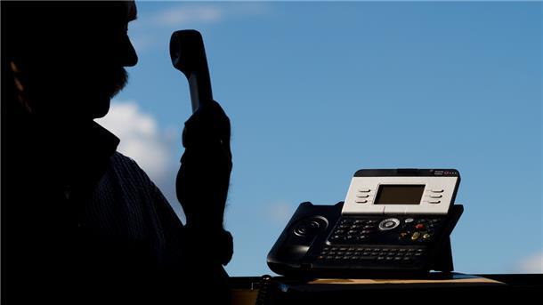 ILLUSTRATION: Ein Mann hält einen Telefonhörer in der Hand. 