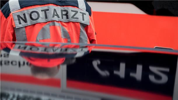 Ein Notarzt steht vor einem Rettungswagen.