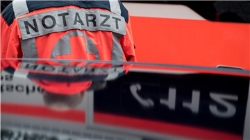 Ein Notarzt steht vor einem Rettungswagen.