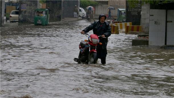 Viele Tote bei Unwettern in Afghanistan und Pakistan Ein Pakistaner watet nach starken Regenfällen mit seinem Motorrad durch eine überschwemmte Straße in Peschawar.