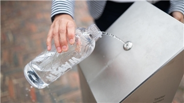 Ein Passant zapft Wasser an einem öffentlichen Trinkwasserspender.