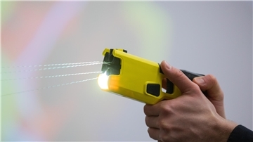 Ein Polizeibeamter demonstriert einen Schuss mit einem Taser. Das Gerät sendet nach Abschuss zweier Elektroden Stromimpulse ab.
