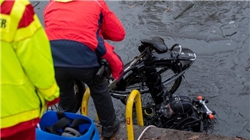 Ein Polizeitaucher hebt ein Fahrrad aus dem Schifffahrtskanal.