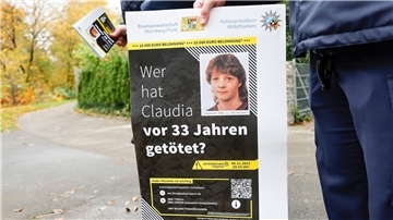 Ein Polizist mit einem Plakat zum Mordfall von 1990 in Röthenbach an der Pegnitz.