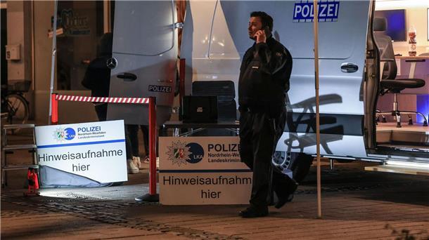 Attacke in Fitnessstudio: 21-Jähriger in akuter Lebensgefahr Ein Polizist steht in der Nähe des Tatortes vor einem Einsatzfahrzeug.