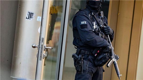 Attacke in Fitnessstudio: 21-Jähriger in akuter Lebensgefahr Ein Polizist steht mit einer Maschinenpistole am Tatort.