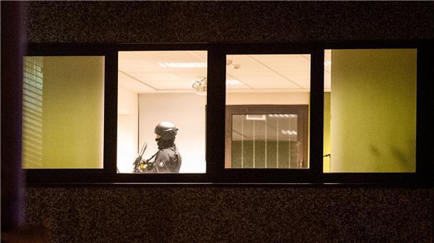 Ein Polizist steht mit einer Waffe in einem Gebäude.