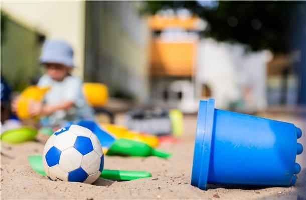 Ein Kind spielt im Sandkasten einer Kita.