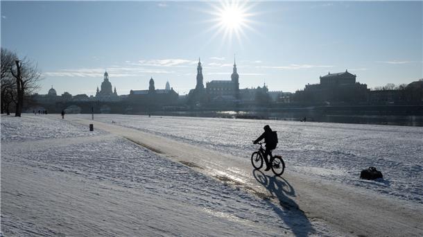 Eisige Nächte in Deutschland Ein Radfahrer fährt am Ufer der vor der Kulisse der Altstadt von Dresden durch den Schnee.