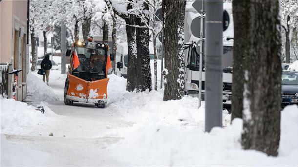 Ein Räumfahrzeug fährt über einen verschneiten Weg in München.