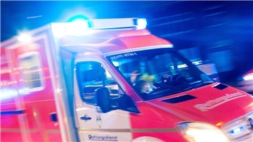 Ein Rettungswagen der Feuerwehr fährt mit Blaulicht durch eine Straße.