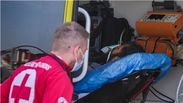 Ein Sanitäter steht im Hafen von Kalamata neben einem verletzten Überlebenden des Schiffsunglücks.