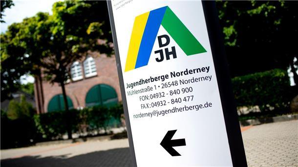 Ein Schild mit dem Logo des DJH steht vor einer Jugendherberge im Norderney.