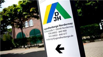 Ein Schild mit dem Logo des DJH steht vor einer Jugendherberge im Norderney.