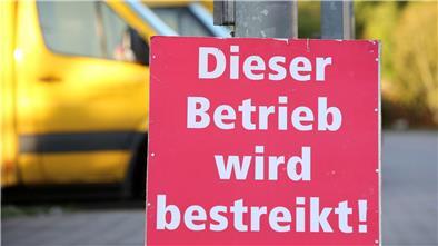 Ein Schild mit der Aufschrift „Dieser Betrieb wird bestreikt“ steht vor einer bestreikten Deutsche-Post-DHL-Niederlassung.