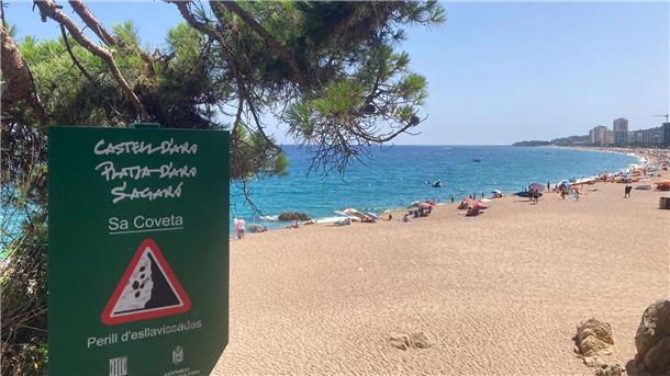 Ein Schild weist an der Platja Gran, dem „Großen Strand“, auf Steinschlag hin.