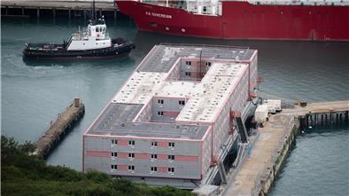 Ein Schleppschiff passiert im Hafen von Portland in Dorset das Schiff „Bibby Stockholm“, das bis zu 500 Menschen aufnehmen soll.