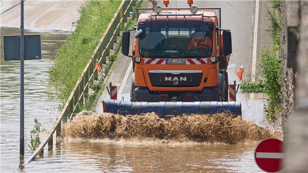 Hochwasser im Südwesten - Aufräumen und abwarten Ein Schneepflug schiebt in Kobern-Gondorf Hochwasserschlamm von einer Straße.