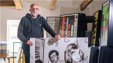 Ein Mann steht in einem großen Raum mit einem Plakat in der Hand.