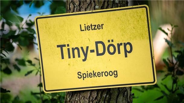 Ein selbstgebasteltes Ortsschild hängt am Gelände mit den Mini-Häusern.