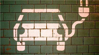 Ein Symbol markiert einen Parkplatz mit einer öffentlichen Ladesäule für Elektroautos.