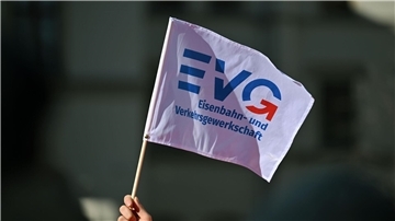 Ein Teilnehmer am Warnstreik Ende März vor dem Erfurter Hauptbahnhof mit einem Fähnchen der Eisenbahn- und Verkehrsgewerkschaft (EVG).