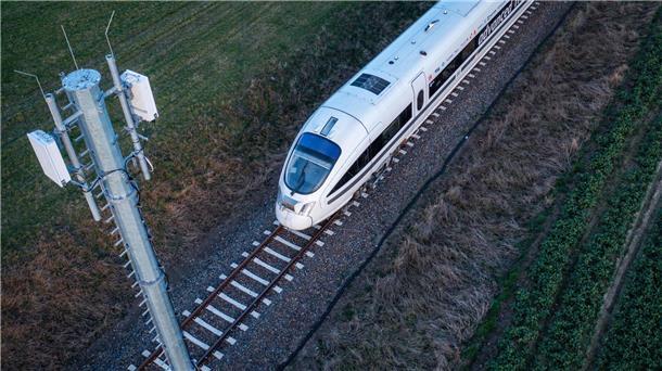 Ein Testzug der Deutschen Bahn fährt an einer der Antennenmasten für das 5G-Bahnprojekt vorbei.