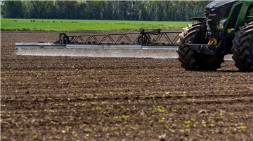 Ein Traktor bringt auf einem Acker Pflanzenschutzmittel aus.