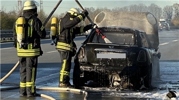 Feuerwehrleute löschen ein Fahrzeug auf einer Autobahn