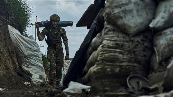 Ein ukrainischer Soldat trägt Vorräte in einem Graben an der Frontlinie bei Bachmut.