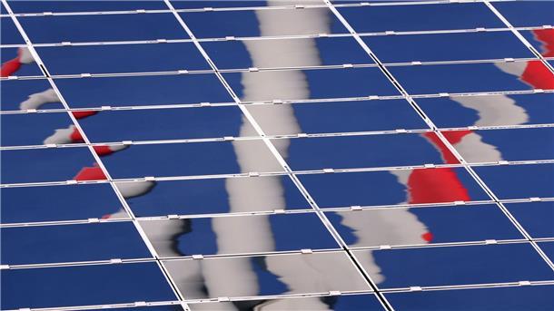 Deutschland hat Klimaziel 2022 wohl erneut verfehlt Ein Windrad spiegelt sich in eine Photovoltaik-Anlage eines Solarparks.