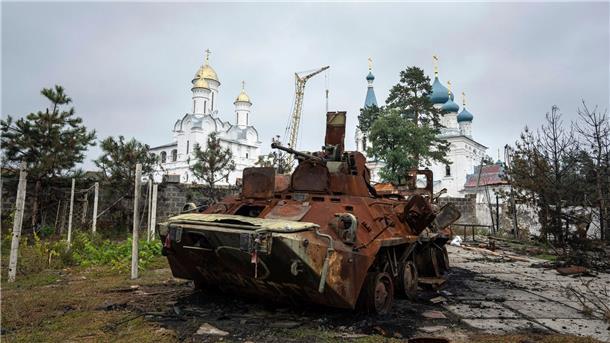 Ein zerstörter russischer Schützenpanzer steht vor einer Kirche in Isjum.