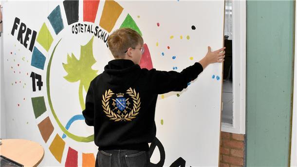 Ein Jugendlicher fasst eine bemalte Wand an.