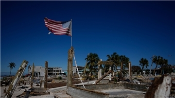 Eine amerikanische Flagge weht inmitten durch den Hurrikan „Ian“ zerstörten Geschäften am Strand von Fort Myers in Florida.