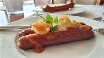 Eine Bio-Rinder-Currywurst – hier in einer abgewandelten Surf & Turf-Variante mit Garnelen – wird künftig im Bistro "EIX" im Badhotel Sternhagen in Cuxhaven auf der Karte stehen.