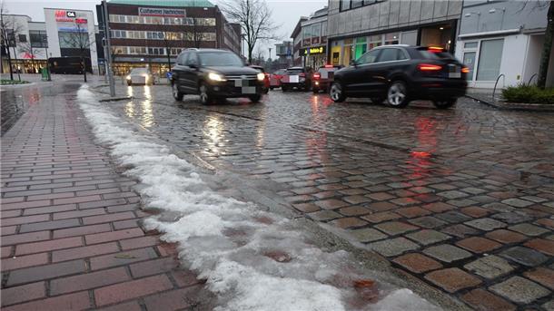 Autos fahren auf einer Straße mit Restschnee am Straßenrand