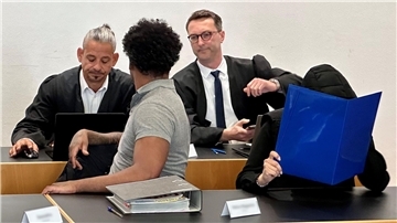 Eine ehemalige Justizvollzugsbeamtin (vorn r) und ein Häftling der Justizvollzugsanstalt Kaisheim (vorn l) sitzen auf der Anklagebank im Strafjustizzentrum Augsburg, im Hintergrund die Strafverteidiger.