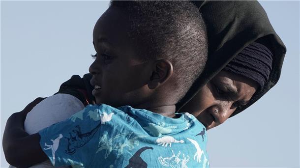 Eine Frau aus dem Sudan trägt ihren Sohn, während sie von Bord der USNS Brunswick gehen.