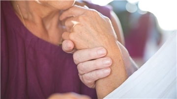 Eine Frau hält die Hand ihres an Demenz erkrankten Mannes.