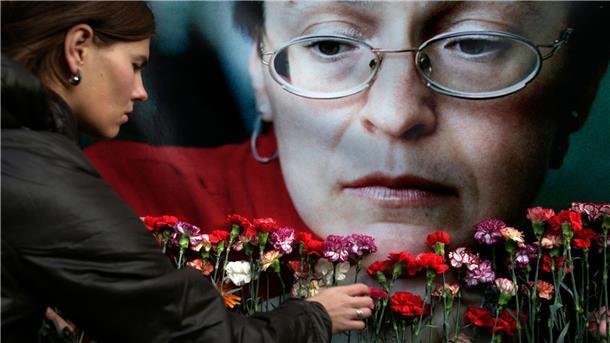 Eine Frau legt in Moskau Blumen vor einem Porträt der ermordeten russischen Journalistin Anna Politkowskaja nieder.