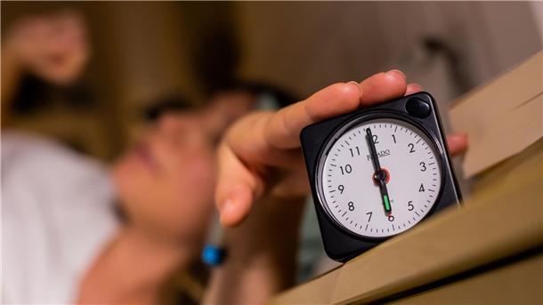 Nur noch fünf Minuten: Schlummertaste in Deutschland beliebt Eine Frau schaltet vom Bett aus einen auf sechs Uhr gestellten Wecker aus.