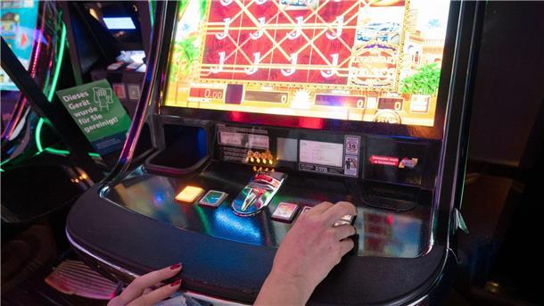 Eine Frau sitzt in einer Spielhalle vor einem Automatenspiel.