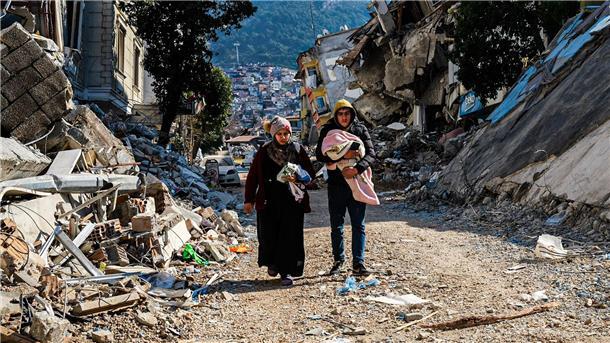 Eine Frau und ein Mann gehen im türkischen Hatay durch die Trümmer.