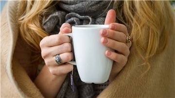 Eine Frau wärmt sich in Hannover, in eine Decke gehüllt, an einer Tasse Tee. Ab wann jemand friert, hängt von vielen Faktoren ab.