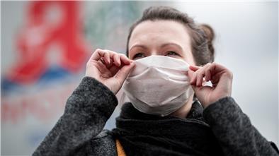 Eine Frau zieht sich eine Gesichtsmaske an - auch in Bremerhaven und Bremen wappnet man sich gegen das Coronavirus.