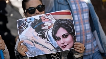 Eine Iranerin beteiligt sich in Frankfurt an einer Demonstration gegen das politische Regime im Iran. Dabei hält sie ein Plakat mit dem Bild der 22-jährigen  Mahsa Amini in den Händen.