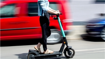 Eine junge Frau fährt mit einem E-Scooter des Anbieters Tier Mobility.