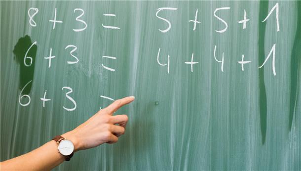 Eine junge Lehrerin schreibt an einer Schultafel im Mathematikunterricht. Wird die Rechnung mit dem Modell Praxislehrer aufgehen? 